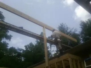 Carpenter setting a ridge beam over a new addition frame — Ice Dam Removal by Roofing Brothers in Housatonic