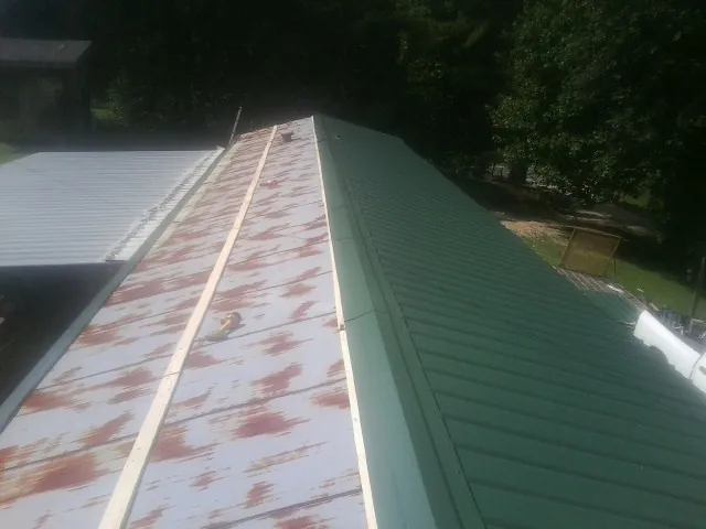 Old rusted panels beside newly installed green metal roofing — Wind Damage Roof Repair by Roofing Brothers in Housatonic