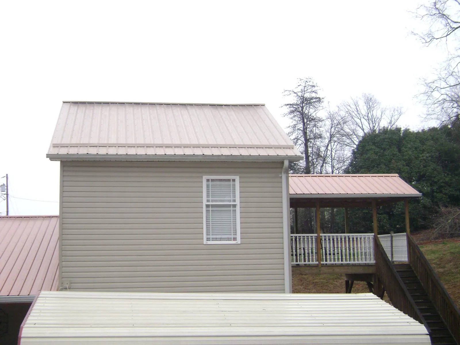 Tan metal roofs on a two story addition and attached porch, from a Roof Replacement job in Housatonic