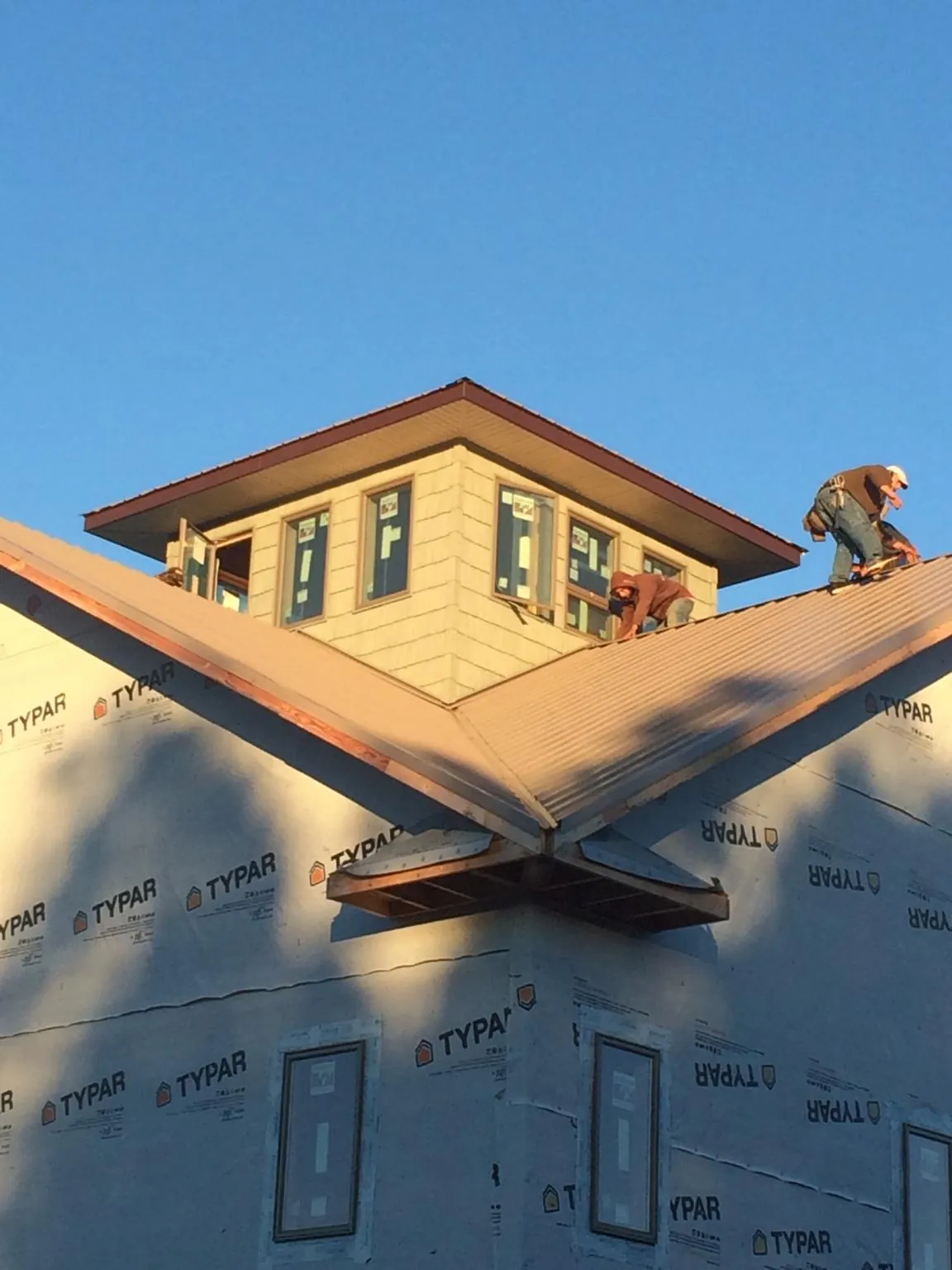 Roofers working around a rooftop cupola on a new metal roof at sunset — Roof Waterproofing in Housatonic by Roofing Brothers